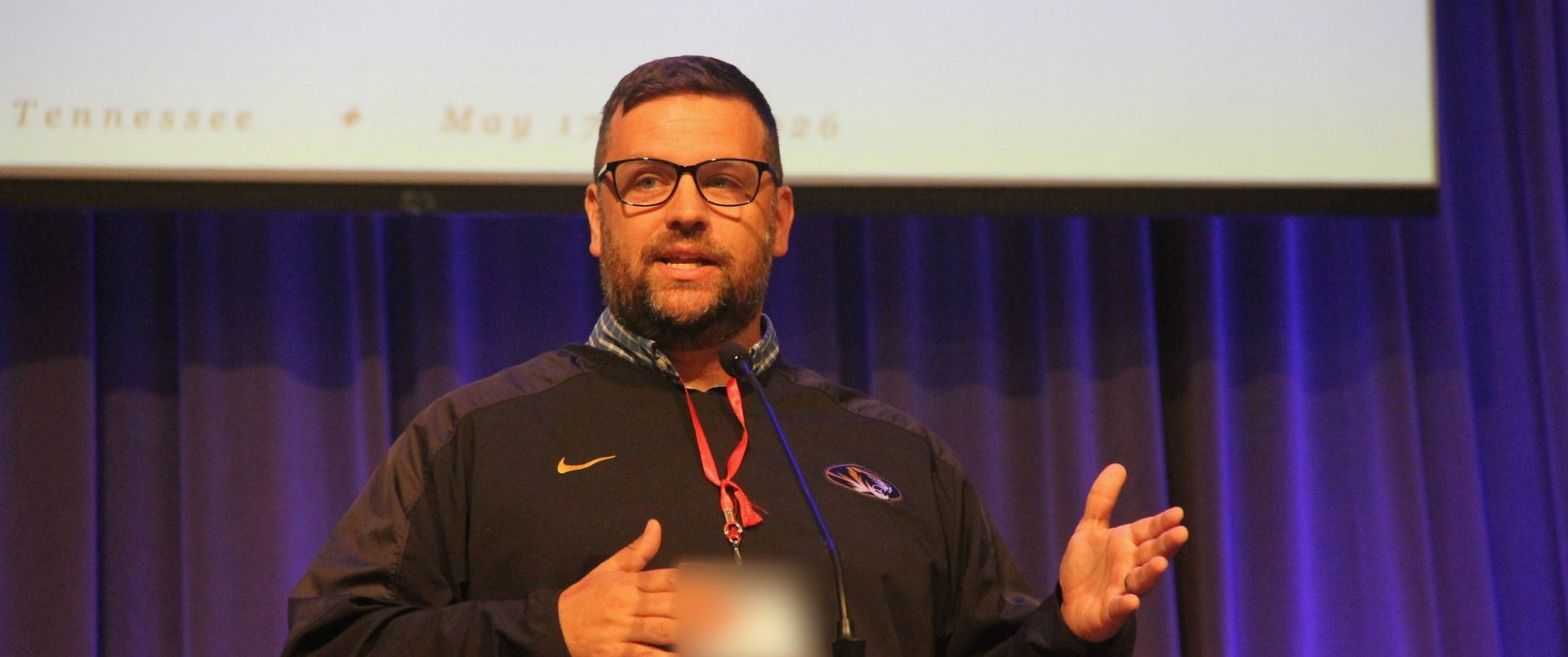 A speaker at the podium during the mission, vision, and values reveal at NITOC 2026
