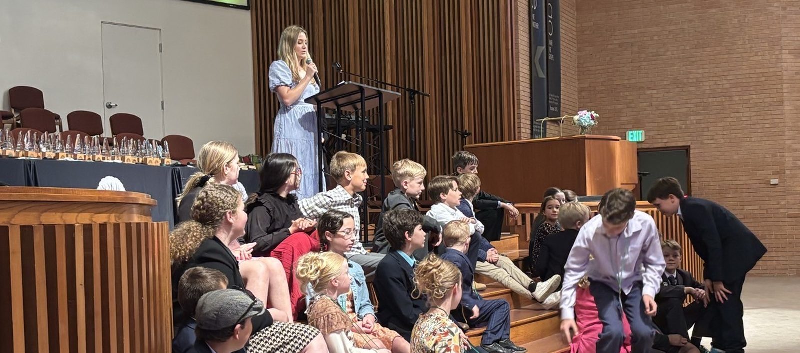 Junior competitors seated on the stage steps at an awards ceremony