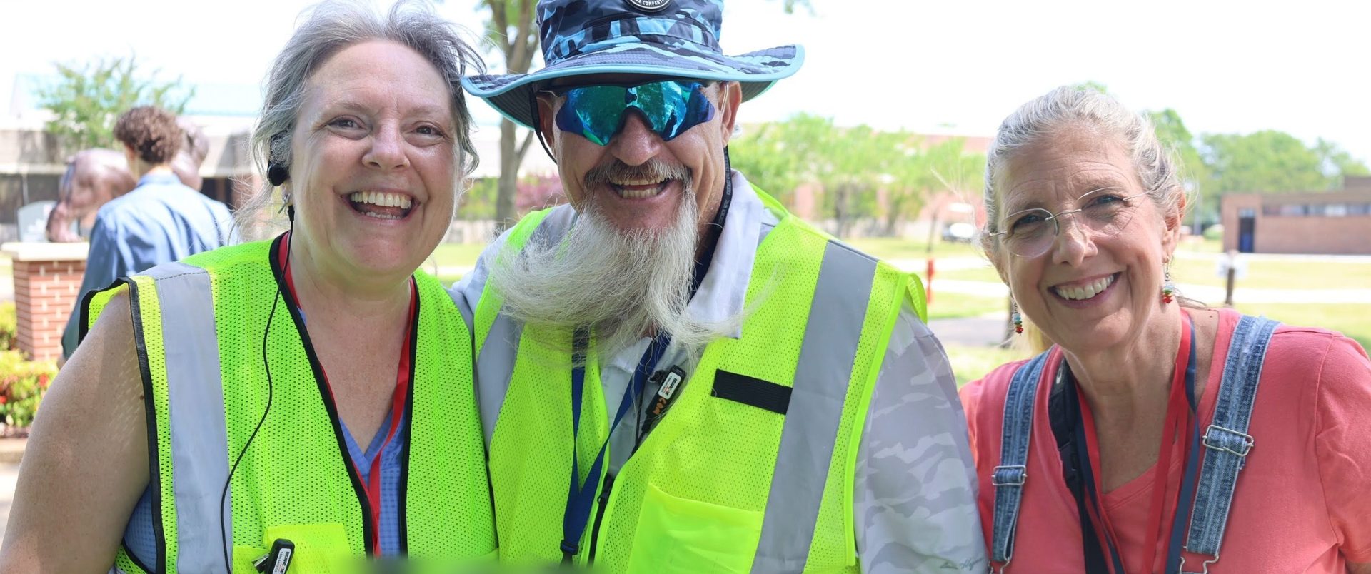 Three smiling safety volunteers in high-visibility vests