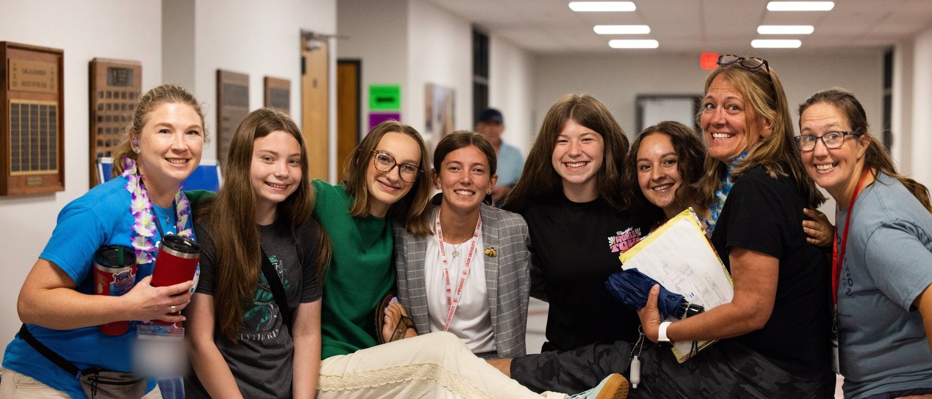 A coach and a group of smiling students in a hallway at NITOC