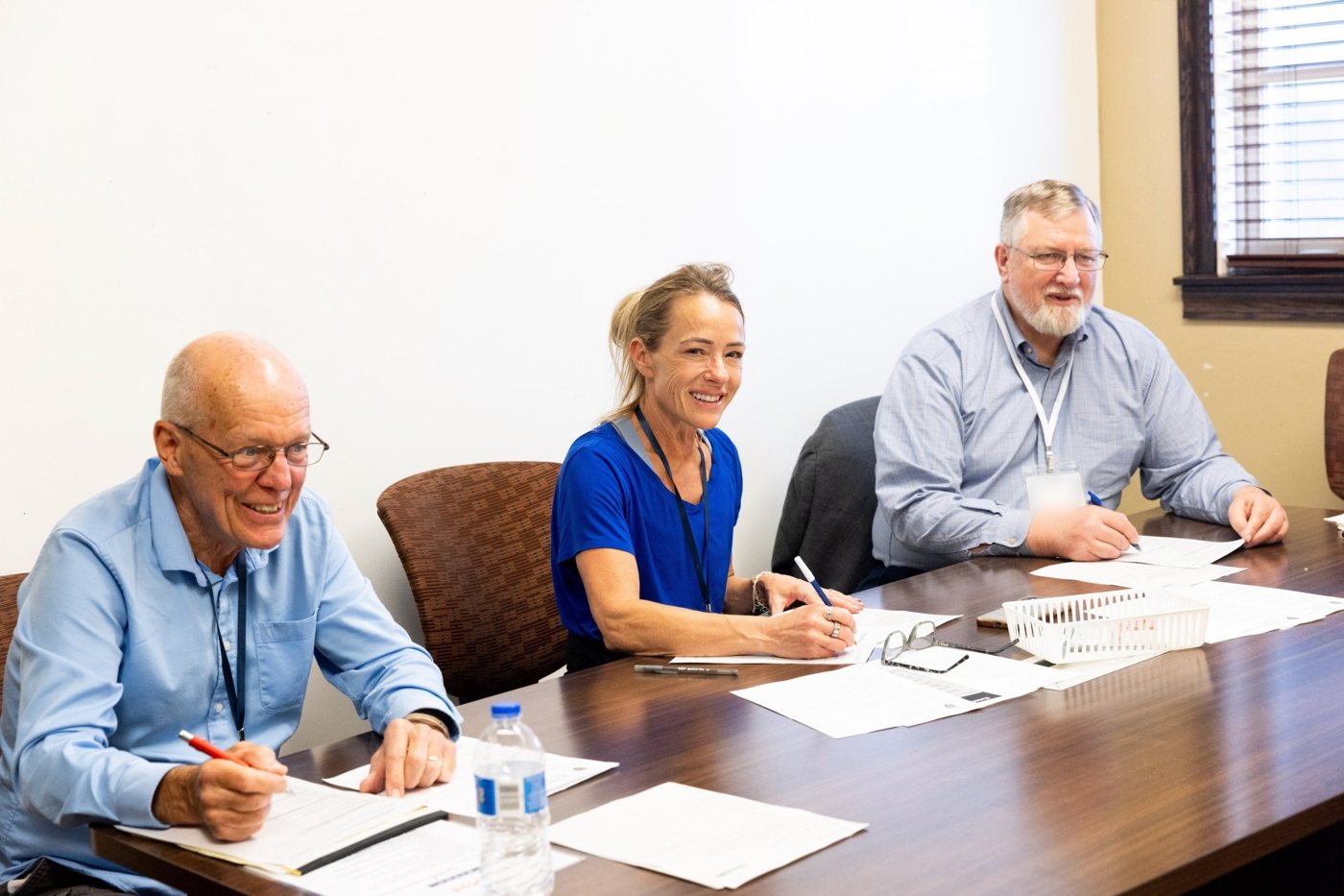 Three community judges smiling as they fill out ballots